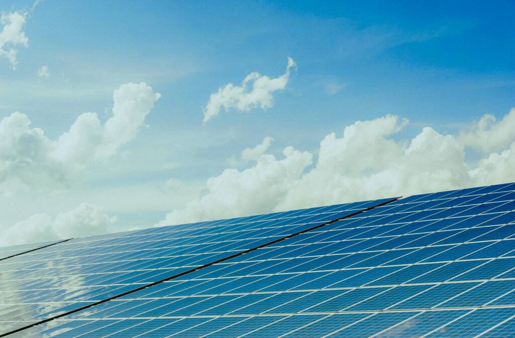 Solar panels below a blue sky of clouds.